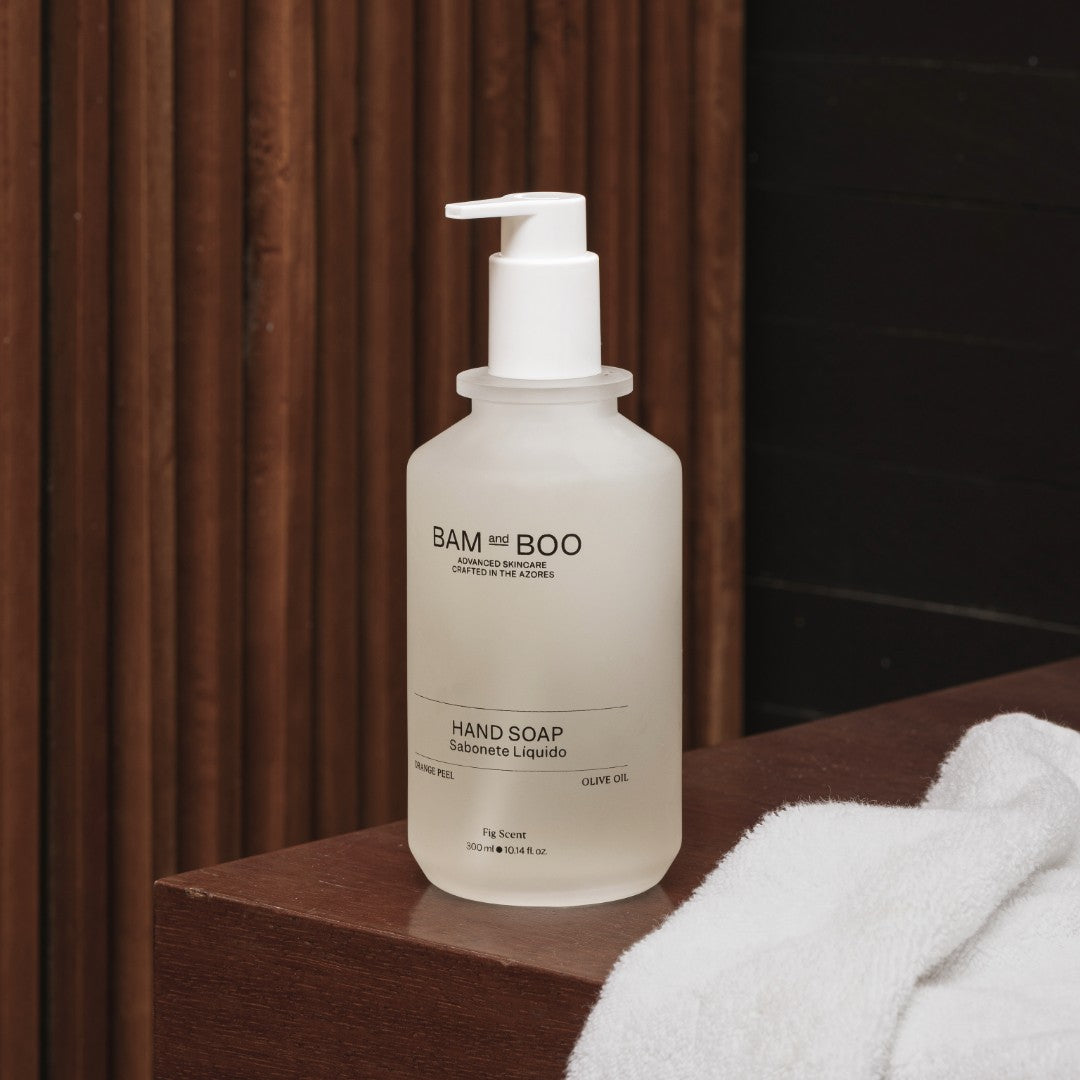 BAM BOO hand soap bottle on a wooden surface with a towel in the background. The best natural amenities made in portugal.